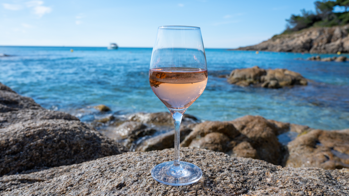 Glass of Rose wine on beach overlooking blue mediterranean sea